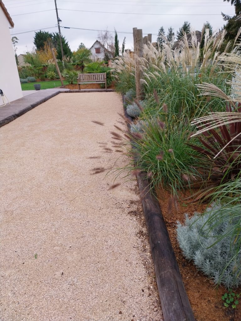 cour gravillonnée beige avec plantes type graminées en bordure