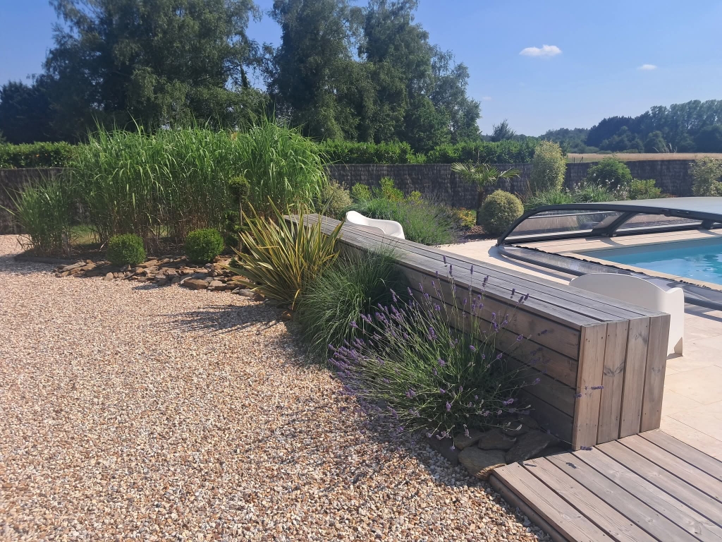 Aménagement paysager bois au bord d'une piscine avec des plantes type lavandes et oliviers