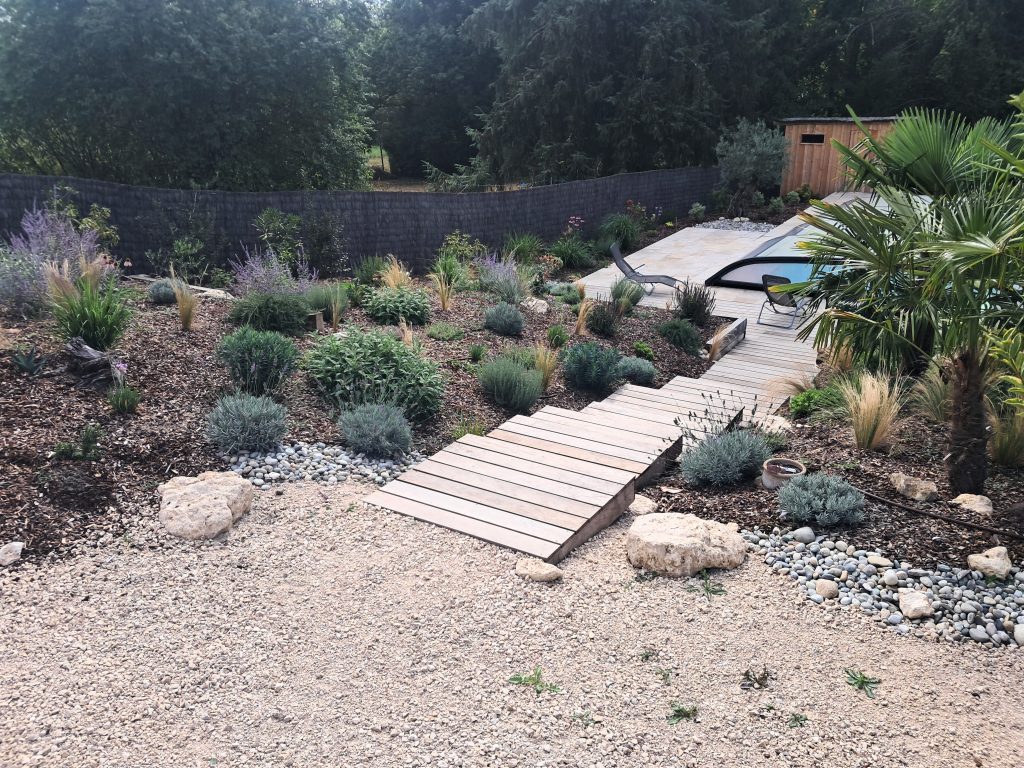 Escaliers en bois qui mène à une piscine extérieure avec jardin méditerranéen de chaque côté