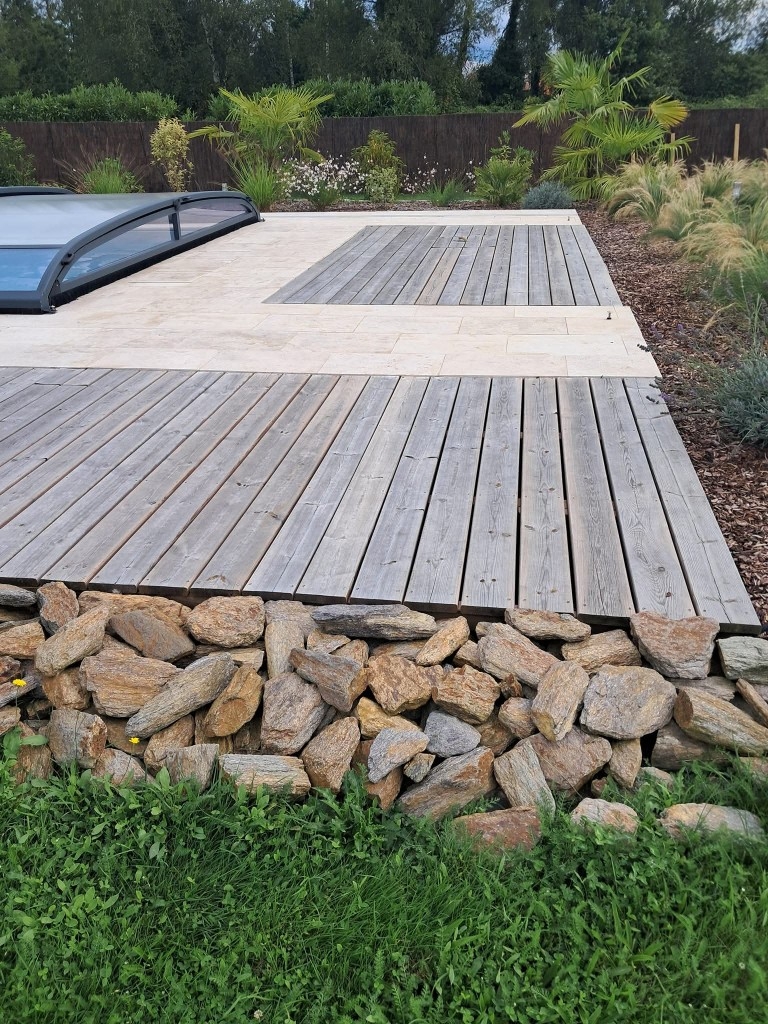 Terrasse en bois au bord d'une piscine avec pelouse au premier plan